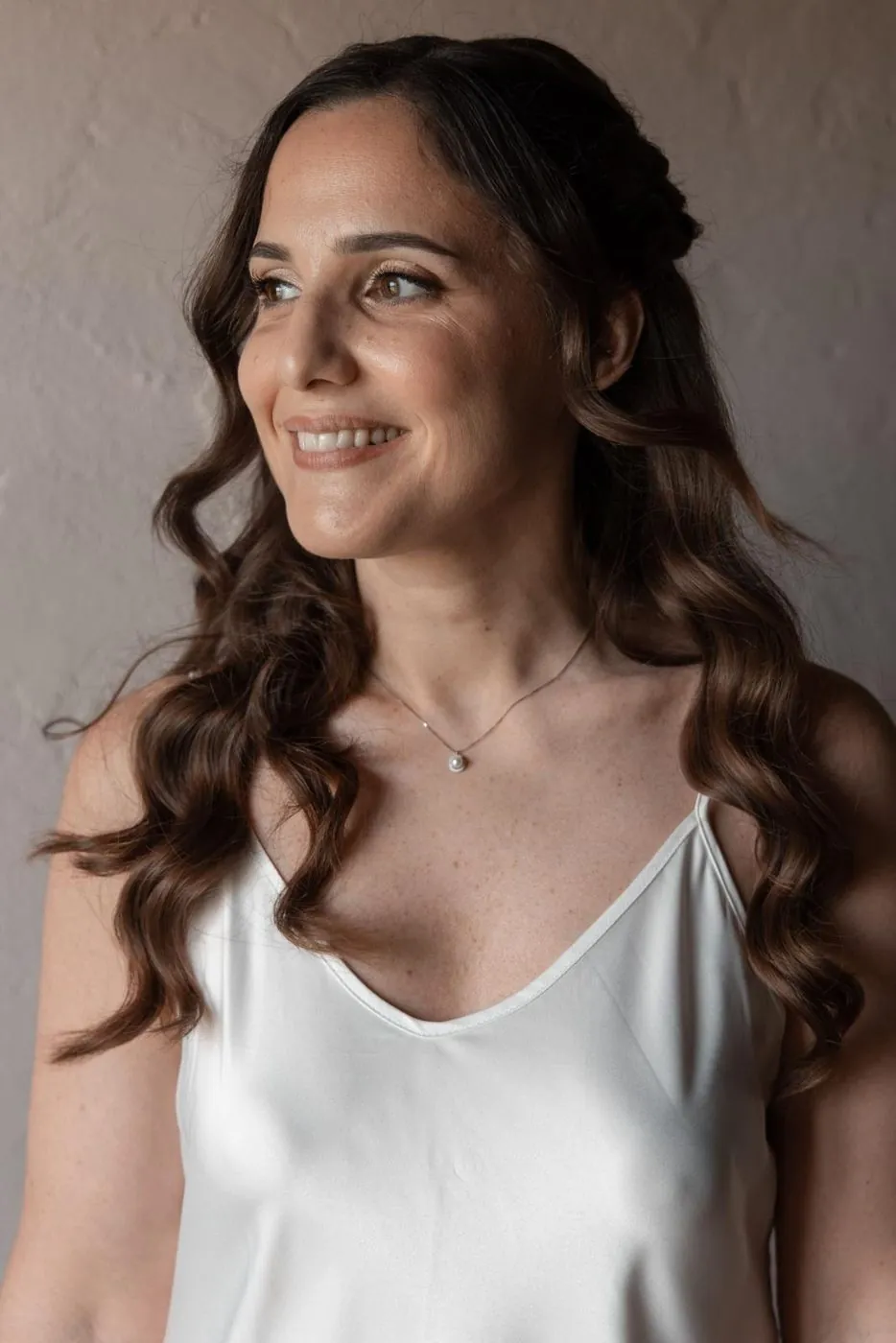 Sposa sorridente con onde morbide e trucco luminoso