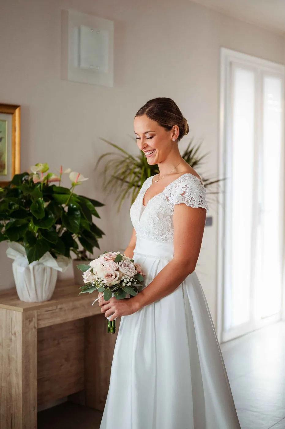 Sposa con bouquet accanto alla finestra