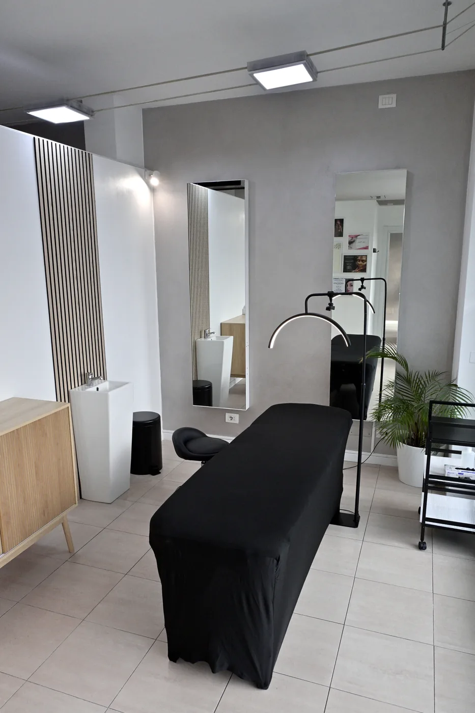 La cabina: lettino nero, lampada ad arco e parete a doghe